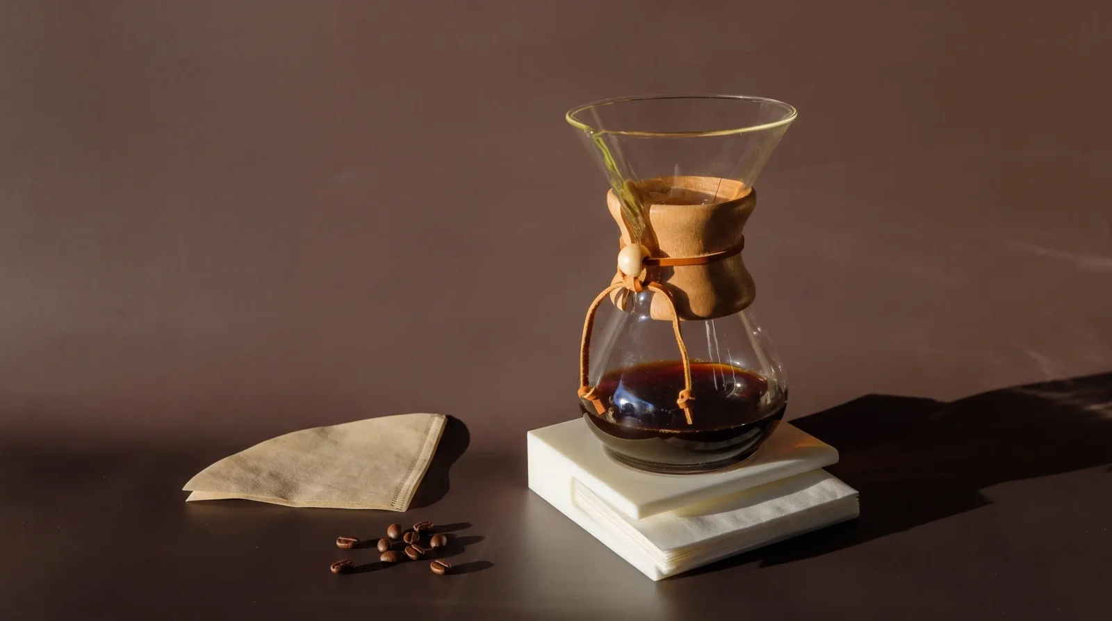 Chemex silhouette on a windowsill, sun through amber brew, dust motes.