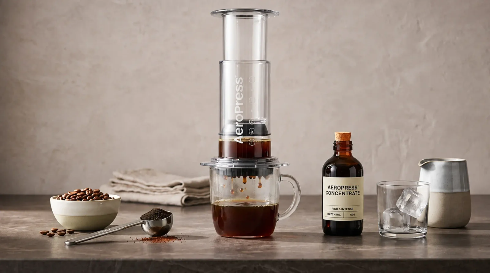 Small carafe of coffee concentrate beside a jug of cold milk on a pale marble counter, bright and airy.