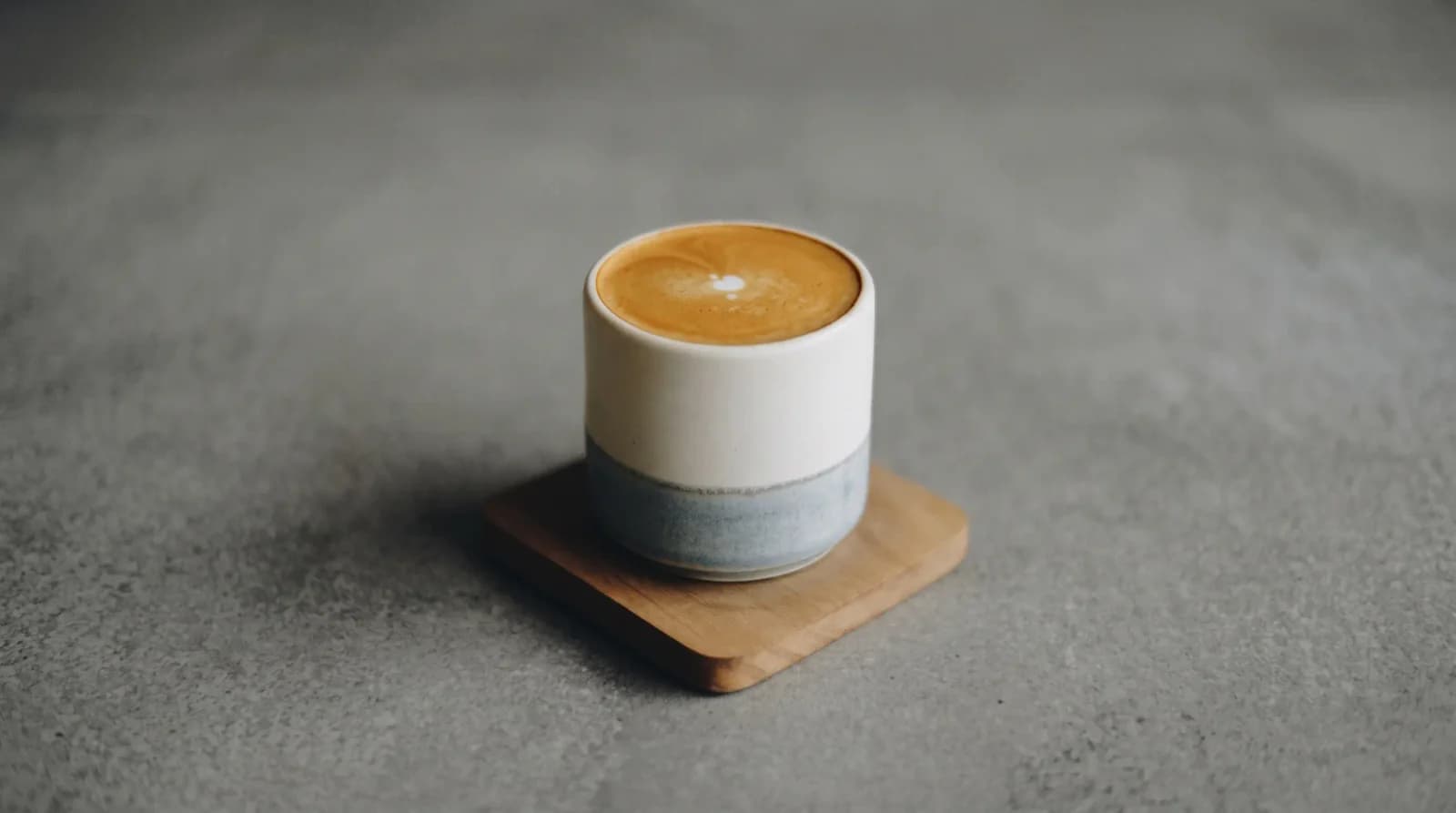 Small tulip cup, glassy milk surface with a single thin ring of crema.
